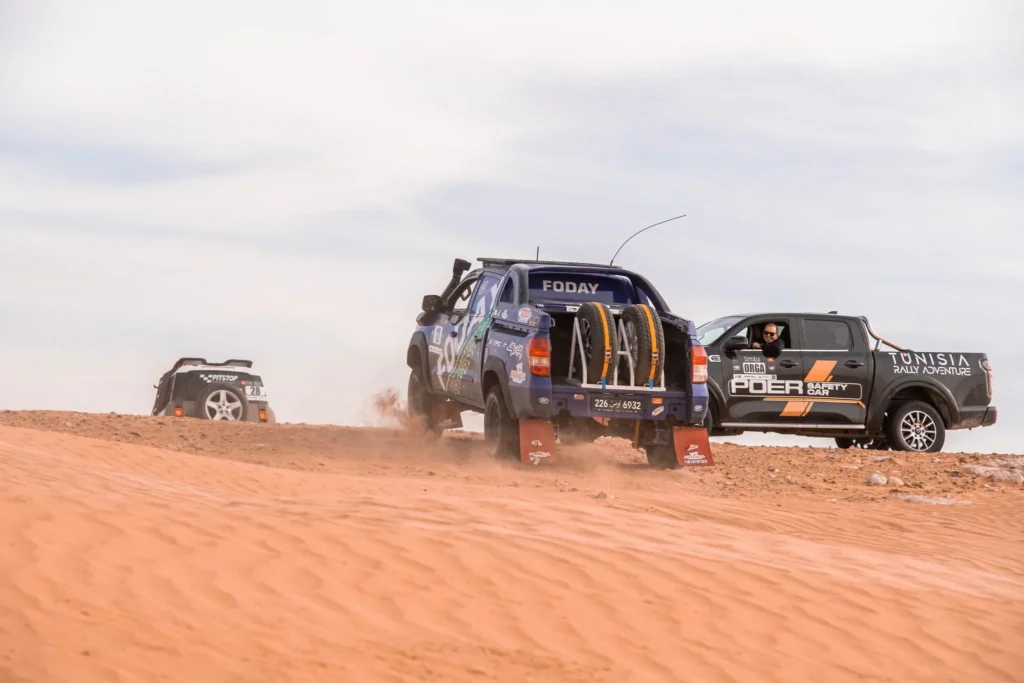 Véhicules du rallye progressant dans les dunes